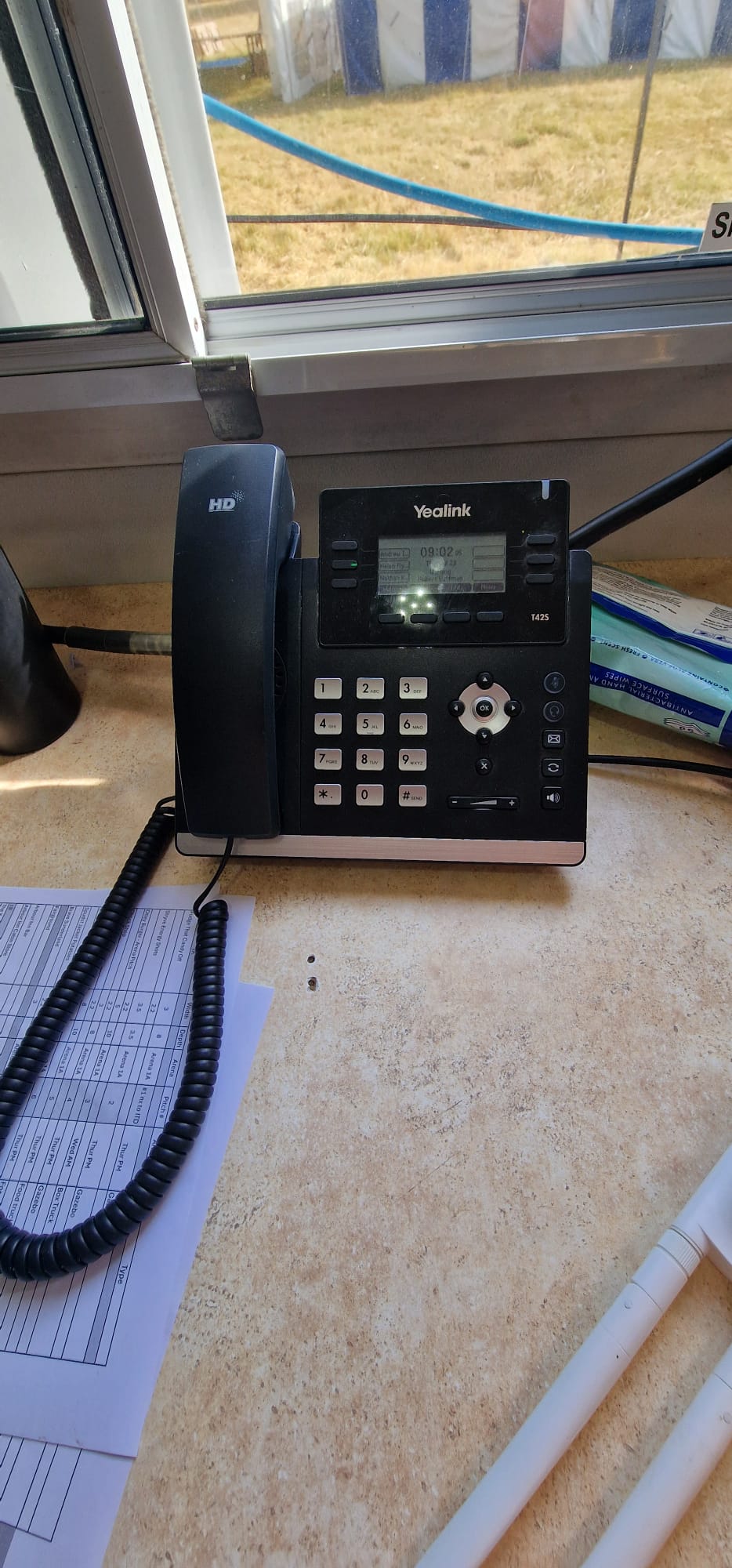 VoIP desk phone operational at Deershed Festival 2026, festival site visible through the window behind