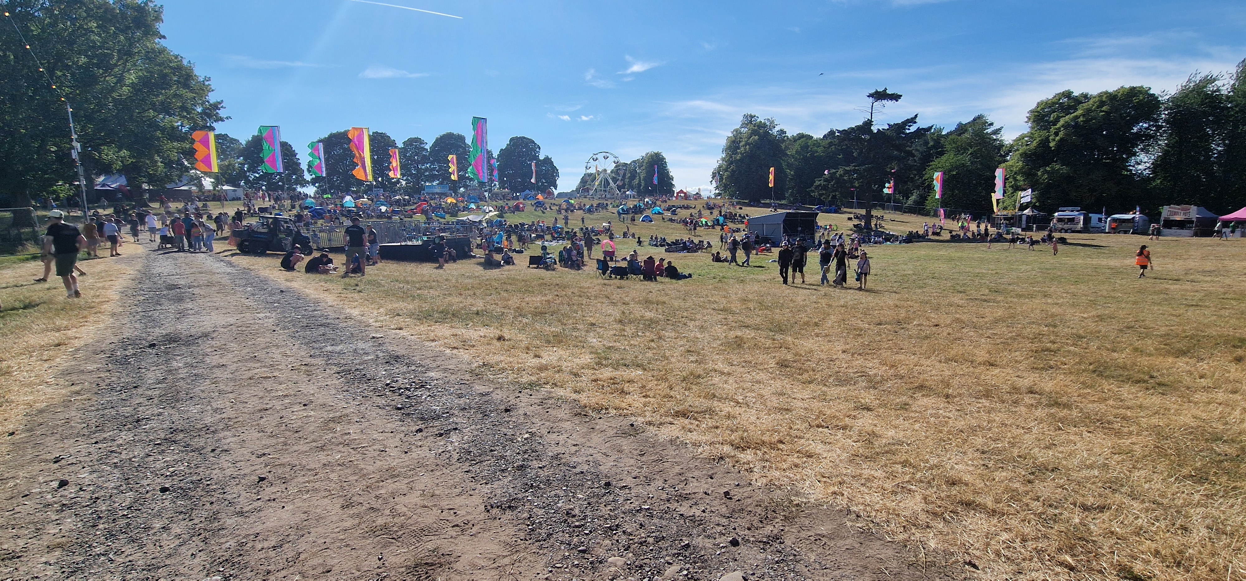 Wide view of the Deershed site with crowds and ferris wheel in the afternoon sunshine