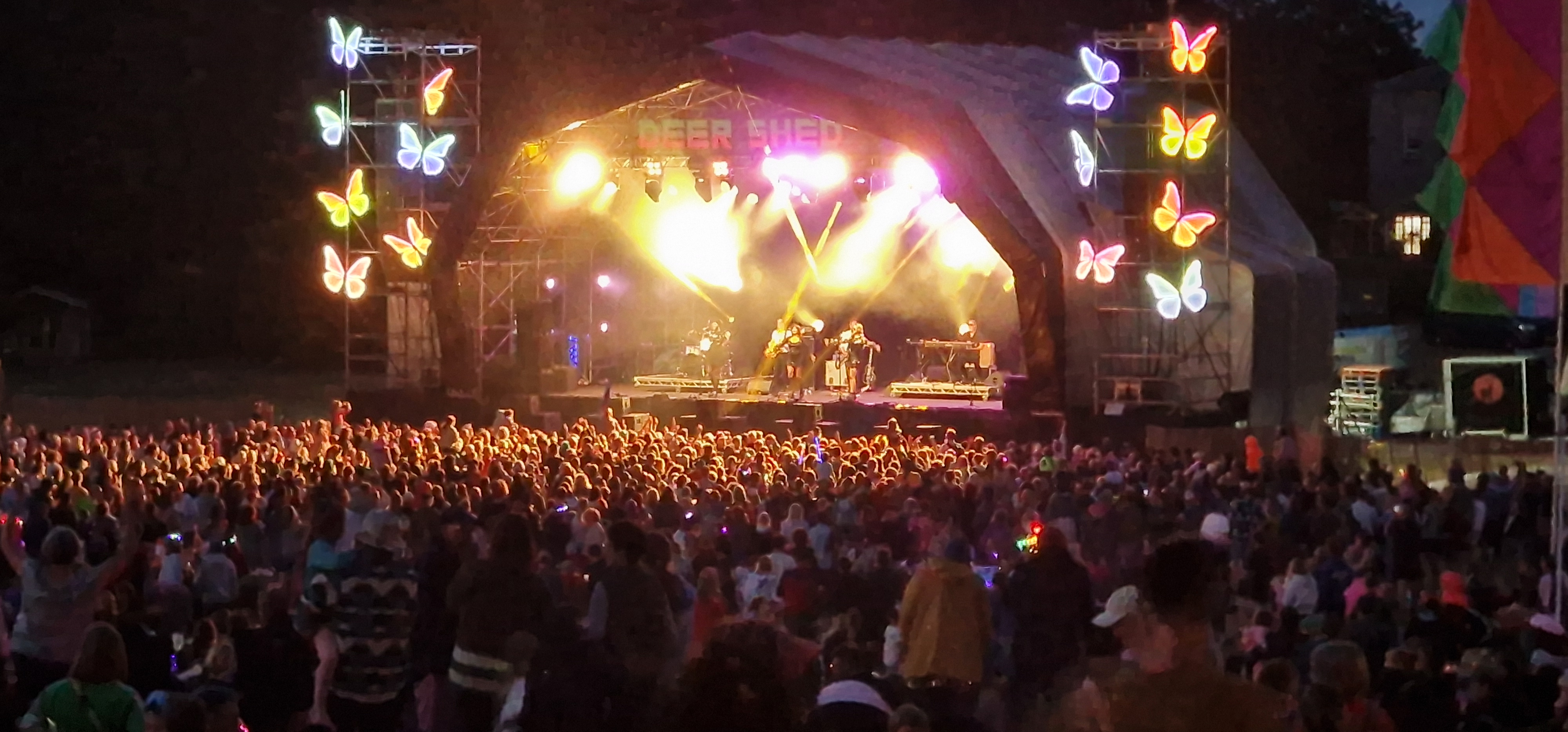 Packed arena at Deershed Festival 2026 with glow sticks and butterfly lighting rig